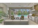 Modern outdoor kitchen with stainless steel appliances and seating area at 12424 Davie Ct, Venice, FL 34293