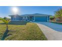 Blue house with a driveway, landscaping, and attached garage at 5187 Cannon St, Port Charlotte, FL 33981