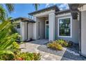 Inviting entryway with a teal door, paver walkway and nicely landscaped gardens at 9450 Snapper Cir, Port Charlotte, FL 33981