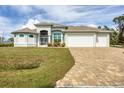 Single-Gathering house with a three-car garage and paver driveway at 12194 Everglades Ave, Port Charlotte, FL 33981