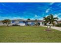 Single-story home with blue exterior, white accents, landscaping, and palm trees at 189 Carlisle Nw Ave, Port Charlotte, FL 33952