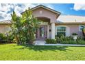 House entrance with pink door, lush landscaping and walkway at 3 Pinehurst Ct, Rotonda West, FL 33947