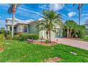 Landscaped green house exterior with palm trees and brick driveway at 3155 Osprey Ln, Port Charlotte, FL 33953
