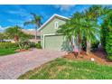 Green house exterior with palm trees, brick driveway, and American flag at 3155 Osprey Ln, Port Charlotte, FL 33953