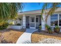 Home's entrance with a screened-in porch and walkway, surrounded by tropical landscaping at 156 Bunker Rd, Rotonda West, FL 33947