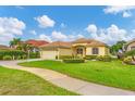 Exterior view of a yellow house with a landscaped lawn and driveway at 1985 Coconut Palm Cir, North Port, FL 34288