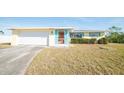 Front view of a yellow single story home with a white garage door and blue shutters at 42 Caroll Cir, Englewood, FL 34223