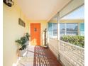 Inviting porch with terracotta tile floor, orange door and potted plants at 42 Caroll Cir, Englewood, FL 34223