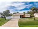 Single-story home exterior, featuring a two-car garage and landscaped lawn at 1220 Greaza St, Englewood, FL 34223