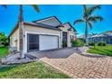 Tan house with orange shutters, a white garage door, and a brick driveway at 2148 La Palma Ave, Port Charlotte, FL 33953