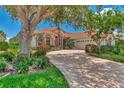 Well-maintained home with a large tree and a paved driveway at 3392 Pennyroyal Rd, Port Charlotte, FL 33953