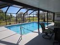 Relaxing screened-in pool area with outdoor seating and a lovely view of the green lawn at 16 Golfview Ct, Rotonda West, FL 33947