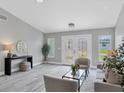 Bright living room with gray walls, wood-look tile floors, and ample natural light at 19 Long Meadow Ln, Rotonda West, FL 33947