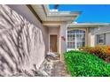 Front entry with a brown door, brick walkway, and lush green shrubbery at 3179 Osprey Ln, Port Charlotte, FL 33953