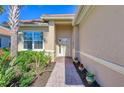 Inviting entryway with a brick-paved walkway, lush landscaping, and a light beige house exterior at 13091 Creekside Ln, Port Charlotte, FL 33953