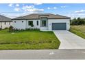 Single-story home with gray garage door, light-colored exterior, and a neatly manicured lawn at 15384 Hennipen Cir, Port Charlotte, FL 33981