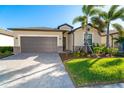 Single-story house with gray garage door, landscaping, and paver driveway at 19584 Fishhawk Trl, Venice, FL 34293