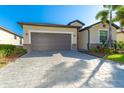 House exterior showcasing a gray garage door and paver driveway at 19584 Fishhawk Trl, Venice, FL 34293