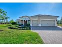 Tan house with tile roof, two car garage, and lush landscaping at 26852 Faldo Ln, Englewood, FL 34223