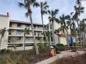Exterior view of a three-story condo building with balconies, surrounded by palm trees and a picnic area at 1751 Beach Rd # 204, Englewood, FL 34223