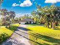 Single-story home with circular driveway, lush lawn, and mature trees at 6375 Biggs St, Englewood, FL 34224