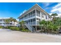 Two-story white condo with screened porch and stairs, surrounded by tropical landscaping at 7482 Palm Island Dr # 2511, Placida, FL 33946