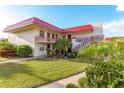 Exterior view of a two-story condo building with a red roof, balconies, and landscaped grounds at 84 Boundary Blvd # 165, Rotonda West, FL 33947