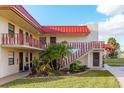 Two-story condo building exterior with balconies, lush landscaping, and stairs at 84 Boundary Blvd # 165, Rotonda West, FL 33947