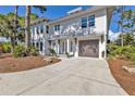 Inviting two-story coastal home with a driveway, mature trees, and landscaping at 7064 Baypine Ln, Englewood, FL 34224