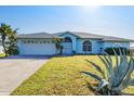 Front exterior view of a single-story home with blue siding, white garage door and green lawn at 9131 Berendo Ave, Englewood, FL 34224