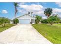 Front view of a single-story home with a driveway, garage, and tropical landscaping at 9 Bunker Ct, Rotonda West, FL 33947