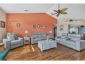 Bright living room featuring gray reclining sofas, hardwood floors, and a vaulted ceiling at 9266 Carnation Ave, Englewood, FL 34224