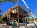 Exterior view of a elevated beach home featuring a wooden deck and stairs at 9526 Jolly Roger Trl, Placida, FL 33946