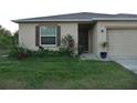 Tan house with dark brown shutters, landscaping, and a one car garage at 22507 Provance Ave, Port Charlotte, FL 33954