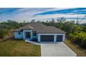 Beautiful single-story home with a two-car garage, lush green lawn, and modern architectural design at 7330 Printer St, Port Charlotte, FL 33981