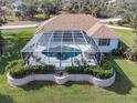 Backyard featuring an enclosed pool and spa area with a patio, manicured lawn, and garden at 110 Barracuda Dr, Placida, FL 33946