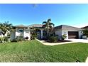 Single-story home exterior, featuring a light-colored facade, lush landscaping, and a two-car garage at 13307 Eisenhower Dr, Port Charlotte, FL 33953