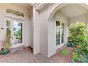 Inviting entryway with red brick pavers, white framed front door and French doors, and lush landscaping at 13376 Creekside Ln, Port Charlotte, FL 33953