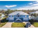Eye-catching two-story home with a blue exterior, white trim, double garages, and a well-manicured front yard at 9240 Pine Cove Dr, Englewood, FL 34224