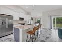 Bright kitchen with granite counters, stainless appliances, gray island, and marble flooring at 11247 Euler Ave, Englewood, FL 34224