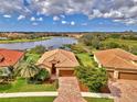 Beautiful single-Gathering home with tile roof, a brick driveway, and lush landscaping with picturesque lake views at 20211 Granlago Dr, Venice, FL 34293