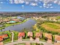 Aerial view showcasing a community with a pool, lake, and single-Gathering homes with tile roofs and landscaping at 20211 Granlago Dr, Venice, FL 34293