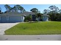 Beautifully landscaped home featuring a well-manicured lawn, elegant driveway, and a charming light-blue exterior at 380 Hoffer St, Port Charlotte, FL 33953