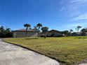 Spacious front lawn featuring palm trees and a charming single-story home under a clear blue sky at 9822 Gulfstream Blvd, Englewood, FL 34224
