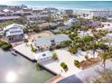An aerial view of a light pink, two-story waterfront house surrounded by a gravel yard and palm trees at 2805 N Beach Rd # B, Englewood, FL 34223
