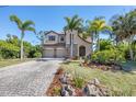 Beautifully landscaped home with a stone facade, paved driveway, and mature palm trees at 117 Cable Dr, Rotonda West, FL 33947