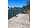A private wooden dock with views of the tranquil canal and waterfront homes under a clear blue sky at 13575 Chenille Dr, Port Charlotte, FL 33981