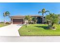 Charming single-story home boasting an attached two-car garage, lush lawn, and mature palm trees at 214 W Pine Valley Ln, Rotonda West, FL 33947