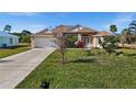 Charming single-story home with lush green lawn and flowering shrubbery adding color to the manicured landscape at 411 Boundary Blvd, Rotonda West, FL 33947