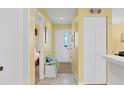 Hallway featuring tile flooring, yellow walls, white trim, and storage leading to the other rooms at 6800 Placida Rd # 235, Englewood, FL 34224